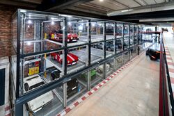 An oblique view of the car park at Motorworld in Mallorca, featuring sports cars in glass display cases