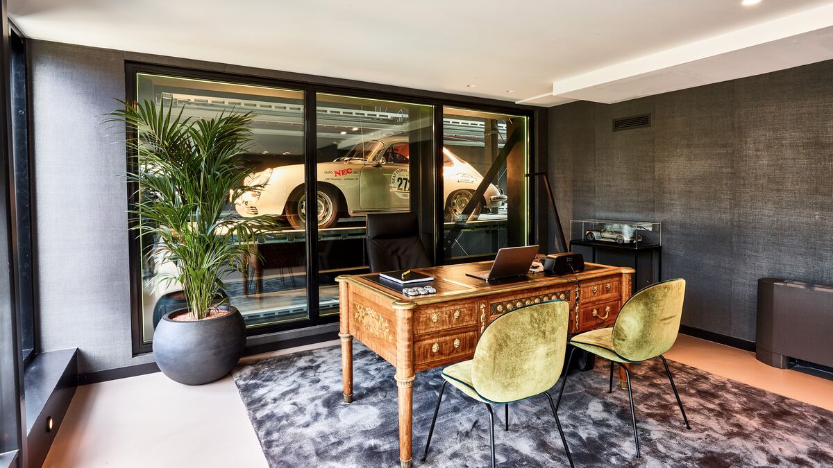 An office with a desk and chairs, with a parked car in the background